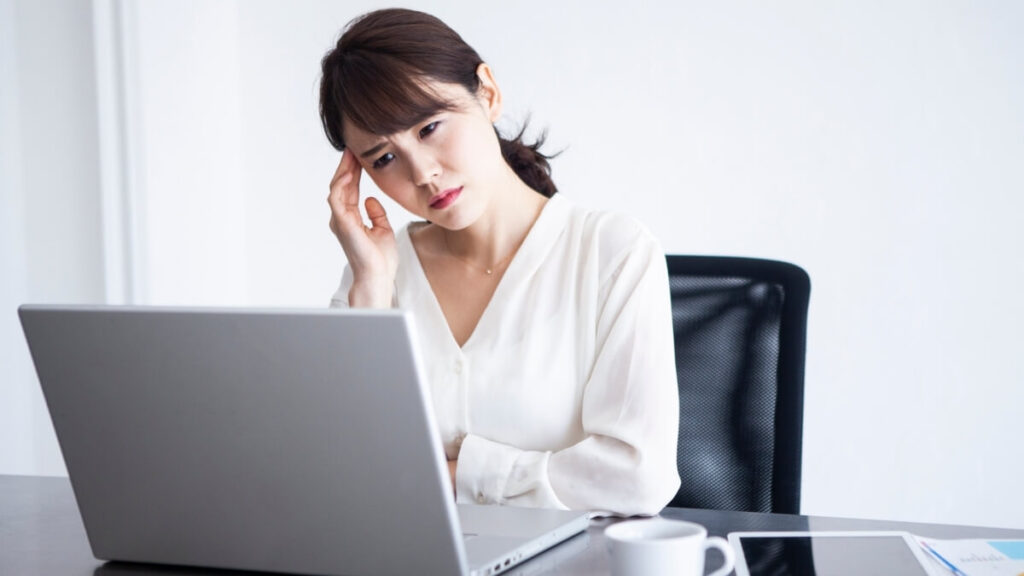 パソコンの前で悩んでいる女性の様子
