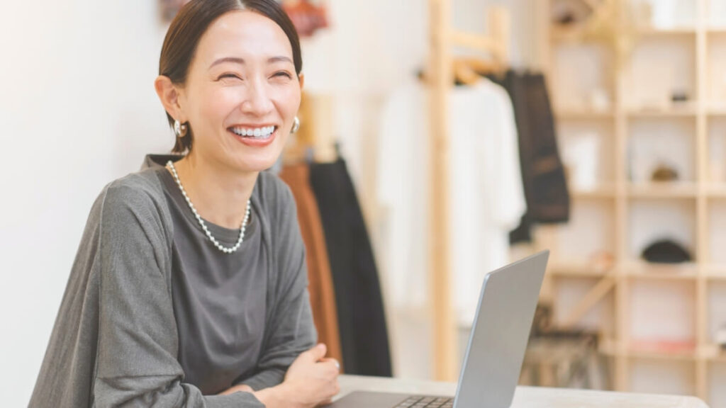 パソコンの前で笑顔の店舗スタッフ風の女性
