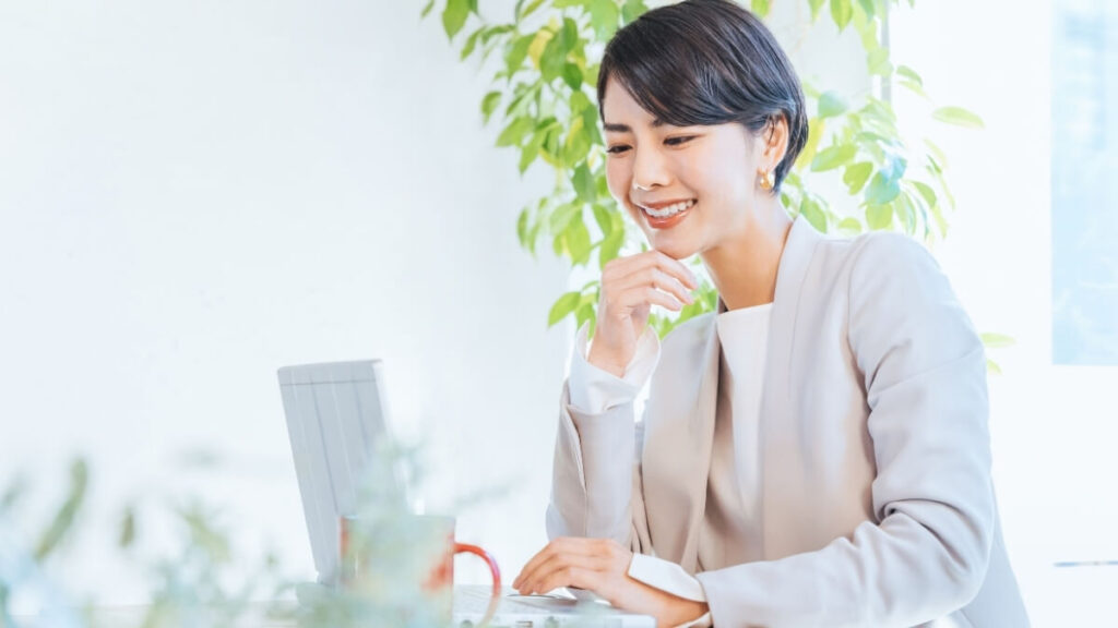 ノートパソコンを笑顔で操作している女性の画像