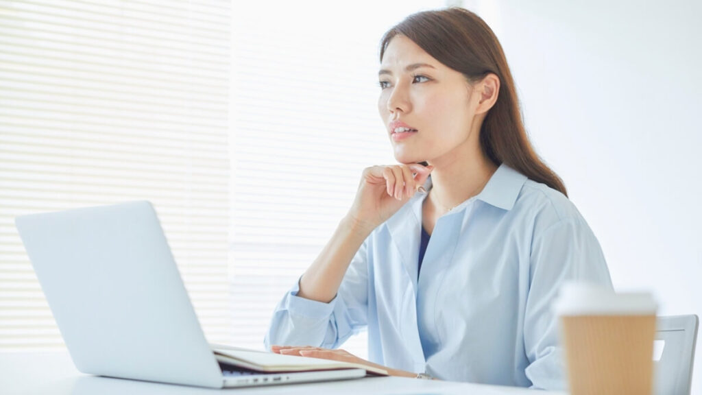 パソコンの前で考えている女性の画像