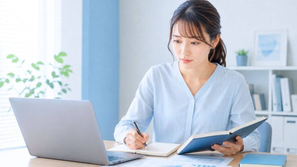 パソコンとノートで一人で作業している女性フリーランスの様子
